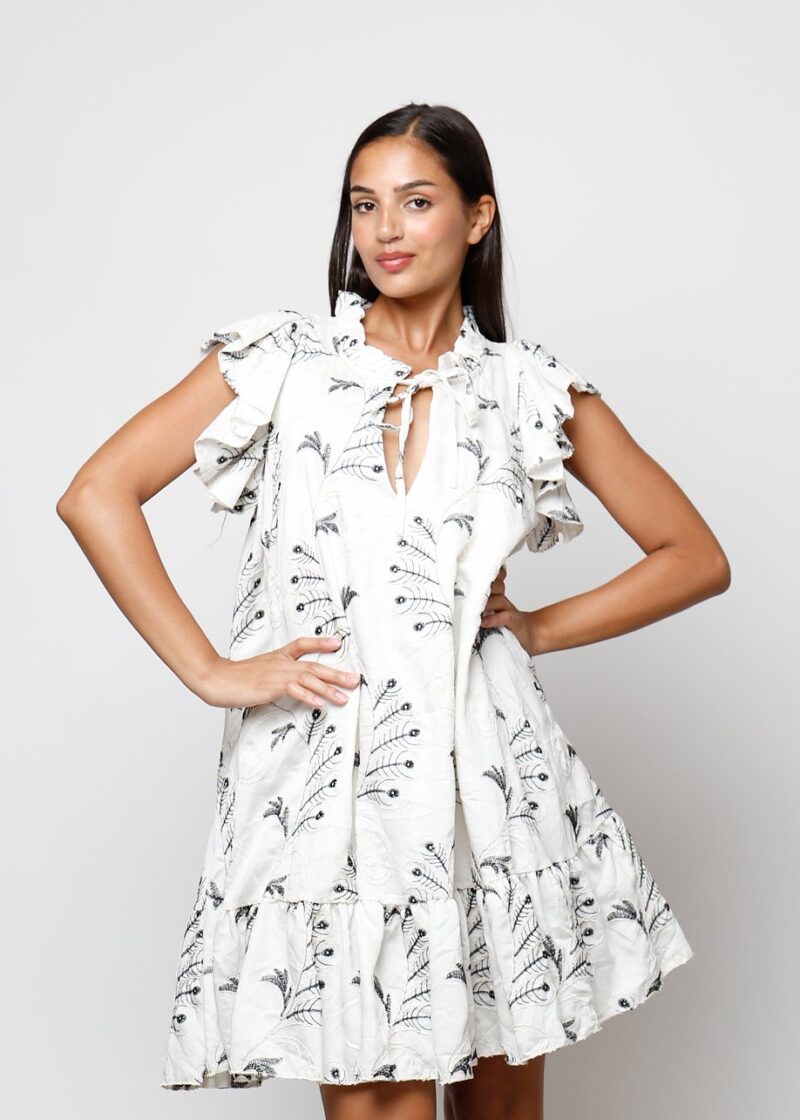 Modelo con vestido blanco corto suelto con bordado de hojas negras y volantes en mangas