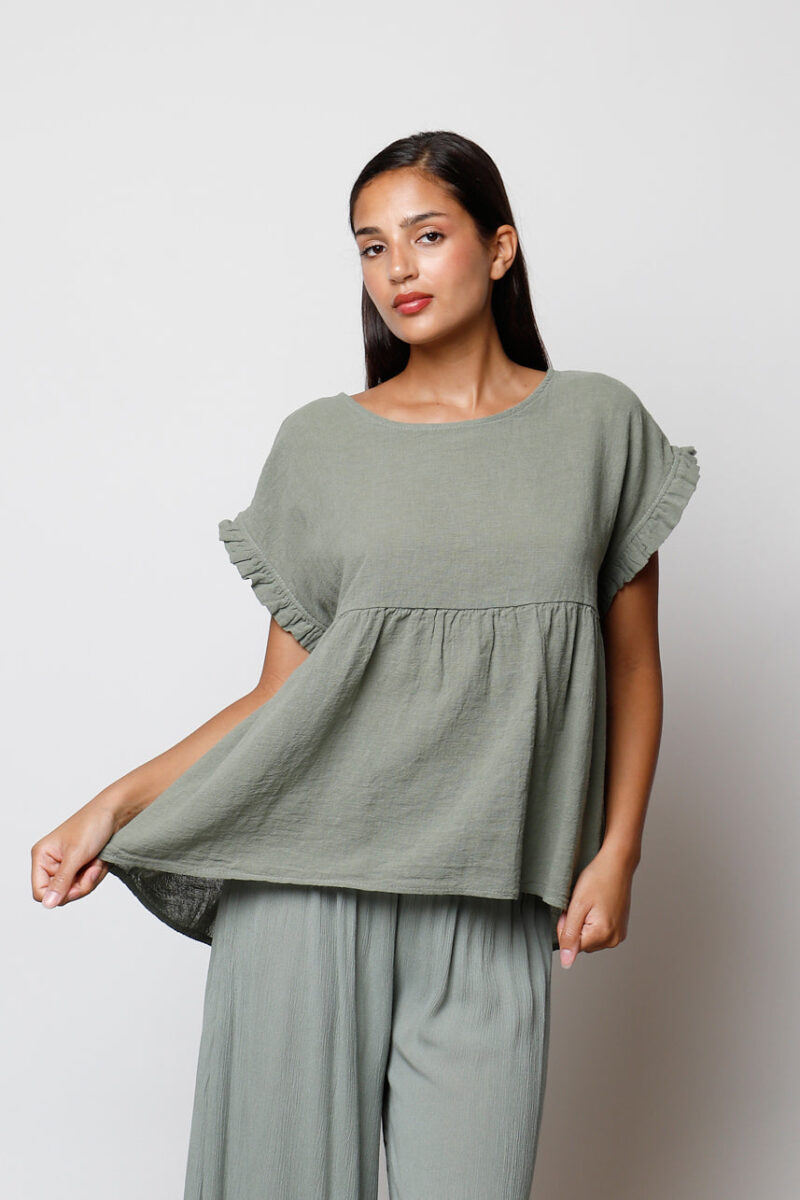 Modelo con blusa Cassia verde oliva de manga corta con volantes y corte suelto, estilo casual para verano.