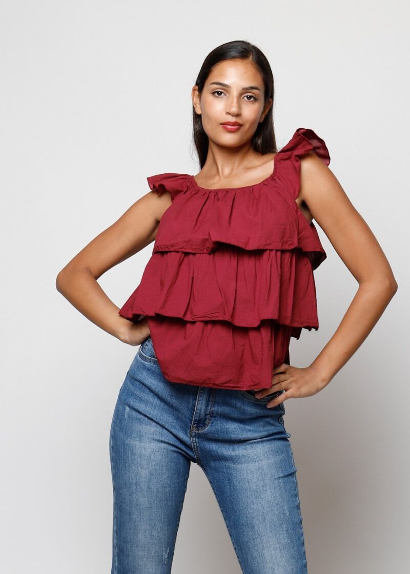 Mujer con top burdeos sin mangas con volantes, estilo casual