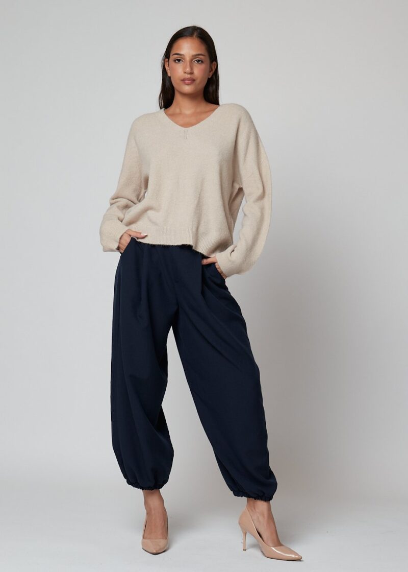 Mujer con pantalón azul marino ancho y jersey beige de punto