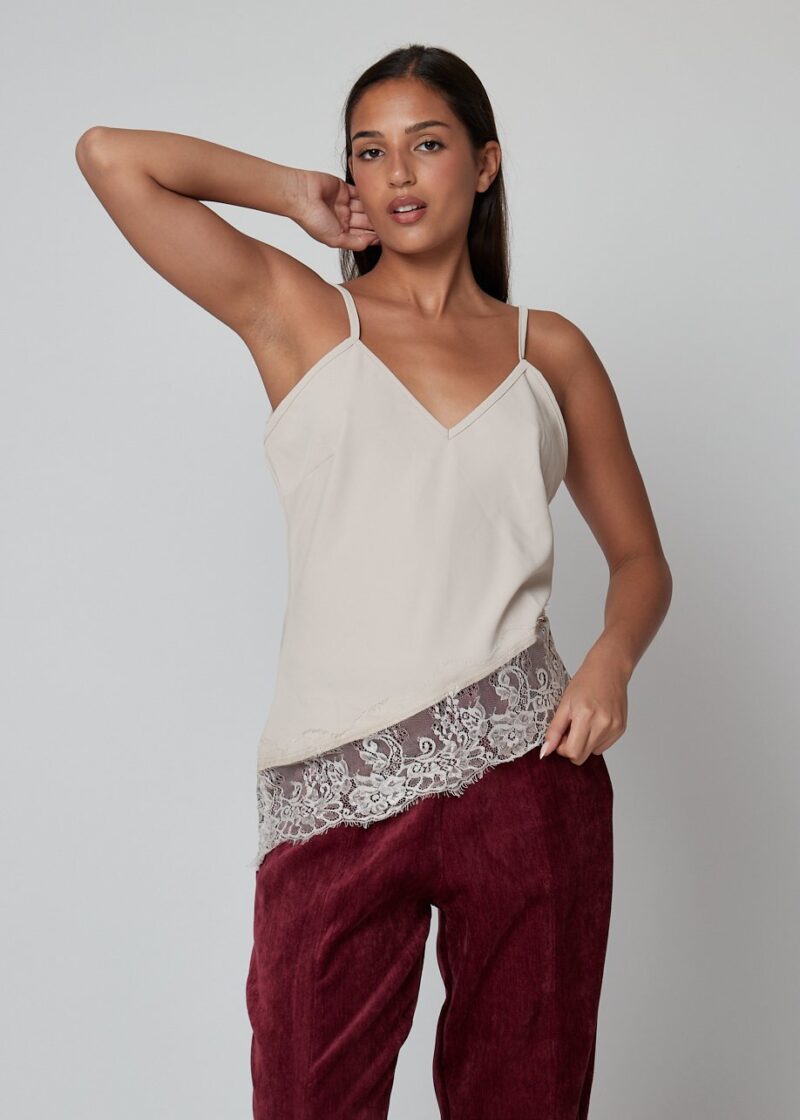 Mujer con top lencero azul marino con encaje y tirantes finos / Mujer con top beige con encaje floral y pantalones burdeos