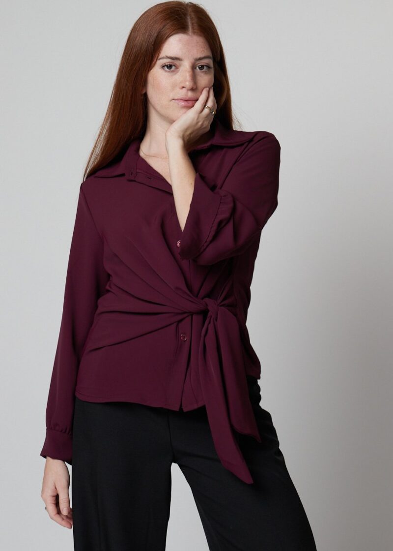Mujer con camisa burdeos con lazo frontal y pantalón negro, look casual elegante